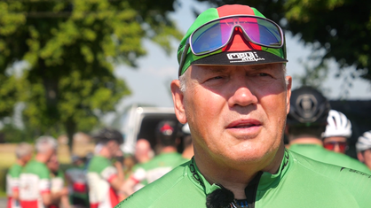 Ein Mann mit einem grünen Fahrradtrikot, einer Kappe und einer Radbrille.