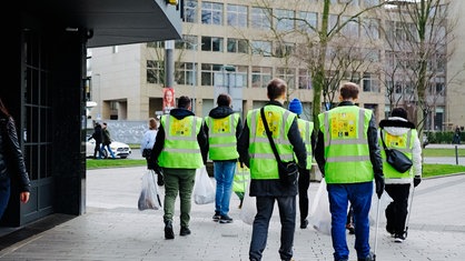 Einige von Eiichiros Helfern in Warnwesten von hinten in der Düsseldorfer Innenstadt