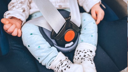 Ein Baby im Kindersitz. Man sieht das Gesicht nicht.