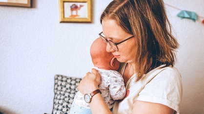 Greta trägt ein Baby auf dem Arm.