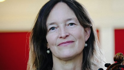 Denise Gruber mit langen braunen Haaren lächelt in Richtung der Kamera.