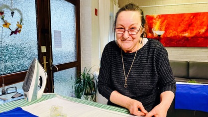 Margret Wagner arbeitet in der Nähwerstatt an einer Fahne.