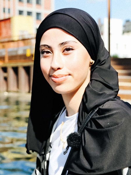 Nour Lahbitich trägt ein schwarzes Kopftuch und sitzt am Dortmunder Hafen.