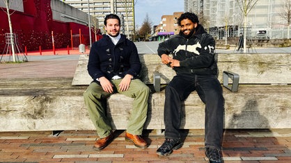 Kevin Grund und Nigash Sriranganathan sitzen nebeneinander auf einer Bank