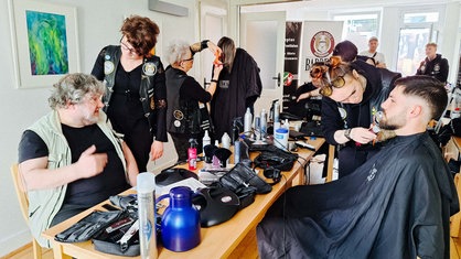 Vier Personen werden die Haare geschnitten.