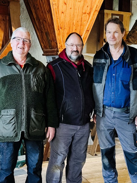 Günther Felten (Mitte) und zwei Ehrenamtler. Sie stehen im Dachstuhl einer Mühle.
