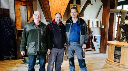 Günther Felten (Mitte) und zwei Ehrenamtler. Sie stehen im Dachstuhl einer Mühle.