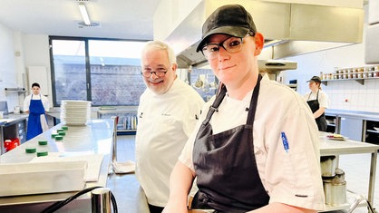 Manuel Klinger und Barbara Wischermann stehen beide in der Küche des Restaurants Pottpurri. Im Hintergrund sieht man auch Salvatore Longobardo. 