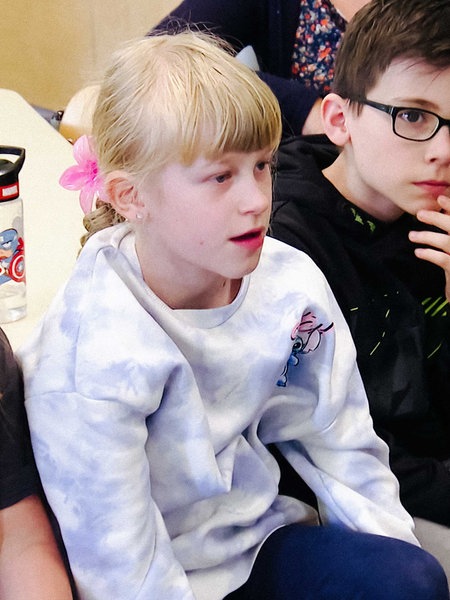 Schulkinder sitzen im Stuhlkreis nebeneinander.