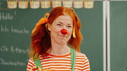 Eine rothaarige Frau mit zwei Zöpfen und Clownsnase