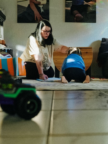 Nadine Rüggeberg sitzt mit ihrem Sohn auf dem Boden ihres Wohnzimmers und spielt.