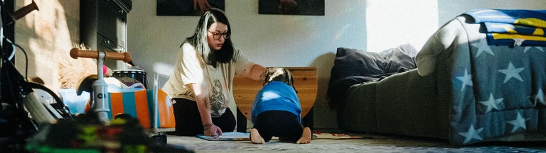 Nadine Rüggeberg sitzt mit ihrem Sohn auf dem Boden ihres Wohnzimmers und spielt.
