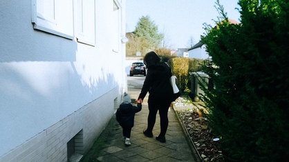 Nadine Rüggeberg geht mit ihrem kleinen Kind an der Hand einen Gehweg entlang.