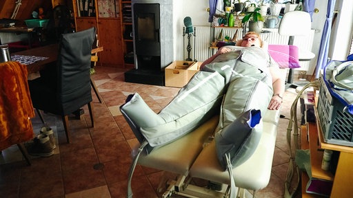 Monika Schulte liegt auf einem Bett, ihr Körper steckt in einer Art Anzug.