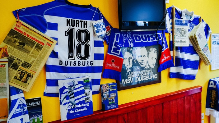 An einer Kneipenwand hängen Fanartikel vom MSV Duisburg.