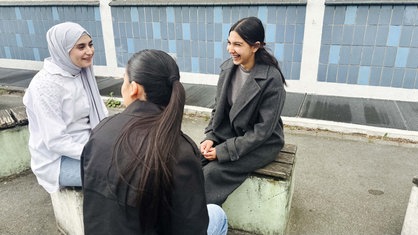 Stanislava Hristova sitzt zusammen mit zwei Freundinnen auf dem Schulhof der Green-Gesamtschule Duisburg. 