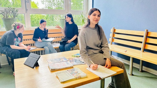 Stanislava Hristova sitzt auf einem Tisch. Hinter ihr sitzen drei Mitschüler. Diese sind in eine Diskusion vertieft. 