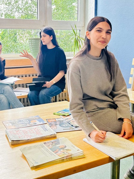 Stanislava Hristova sitzt auf einem Tisch. Hinter ihr sitzen drei Mitschüler. Diese sind in eine Diskusion vertieft. 