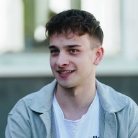 Janic Dalwigk, kurze braune Haare, die ihm über die Stirn fallen, grau-gestreiftes Hemd, darunter ein weißes T-Shirt.