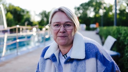 Therapietauchlehrerin Annika Siewert schaut in die Kamera. Hinter ihr das Schwimmbecken eines Freibads.