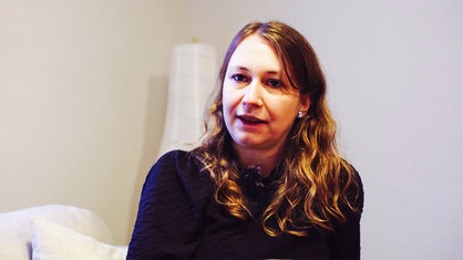 Claudia Günther sitzt auf einer Couch und ist von der Hüfte aufwärts fotografiert. 