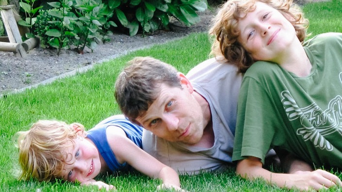 Matthias Bäcker und seine beiden Söhne Max und Sebastian im jungen Alter auf einer Gartenwiese.
