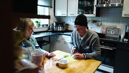 Monika Keila und Stefan Becker sitzen in der Küche und kochen gemeinsam.