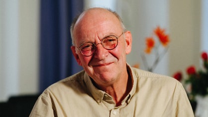 Ein älterer Mann mit Brille und halbglatze lächelt freundlich in die Kamera