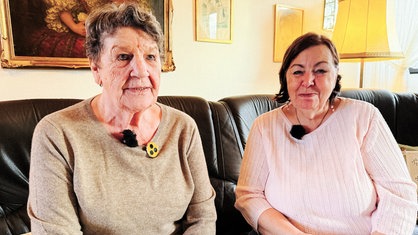 Zwei Frauen sitzen nebeneinander auf einem Sofa