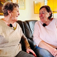Zwei Frauen sitzen auf einem Sofa und lachen sich an