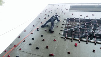 Jugendliche klettern an einer Kletterwand. 