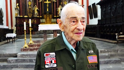 Ein älterer Mann steht in einer Kirche. Er trägt eine US-amerikanische Uniform.