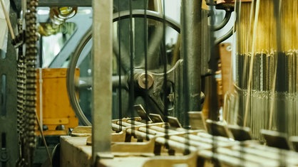 Webstuhl mit Rad, Spindeln und Fäden, die mechanisch zusammengesponnen werden 