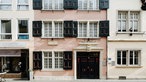Ein schmales Haus mit rosa Fassade und hölzernen Fensterläden.