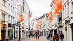 Fußgängerzone in Bonn. An Fahnenstangen hängen fahnen mit der Aufschrift Beethovenfest Bonn.