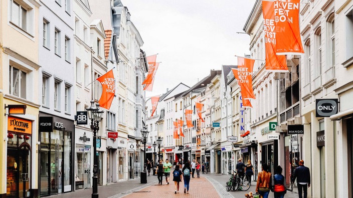 Fußgängerzone in Bonn. An Fahnenstangen hängen fahnen mit der Aufschrift Beethovenfest Bonn.