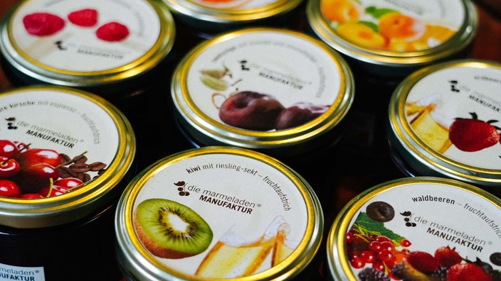 Verschiedene Marmeladengläser von Nahem fotografiert. Ganz vorne steht eine mit der Sorte "Kiwi Riesling Sekt".
