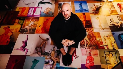 Martin de Crignis sitzt auf dem Boden. Um ihn herum Dutzende seiner Fotos.