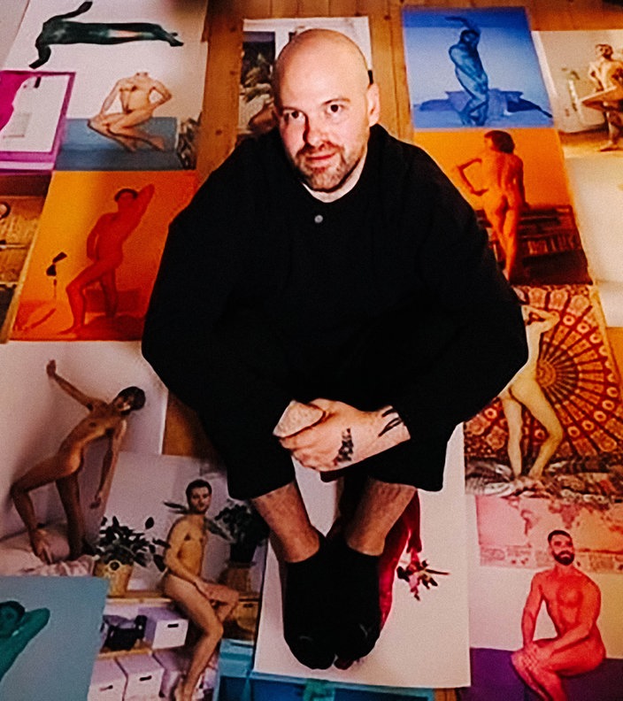 Martin de Crignis sitzt auf dem Boden. Um ihn herum Dutzende seiner Fotos.