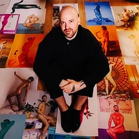 Martin de Crignis sitzt auf dem Boden. Um ihn herum Dutzende seiner Fotos.