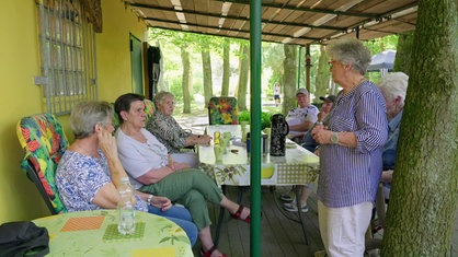 Eine Gruppe von älteren Menschen unterhält sich gemeinsam an einem Tisch. 