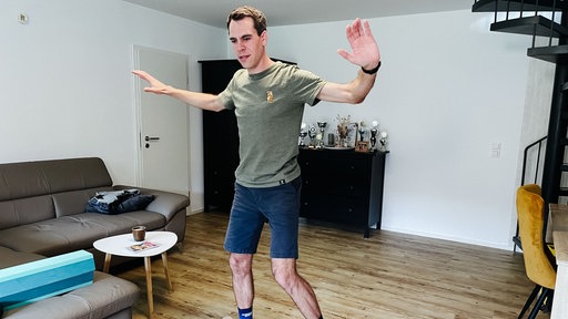 Sebastian Schmitz steht mit weit ausgebreiteten Armen auf einem Balanceboard.