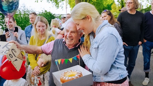 Eisverkäufer Donato Grella lacht und wird von einer blonden Frau gratulierend gedrückt.