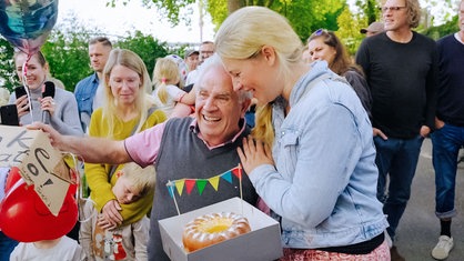 Eisverkäufer Donato Grella lacht und wird von einer blonden Frau gratulierend gedrückt.