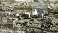 Ein zerstörtes Dorf, von einem Hügel aus aufgenommen