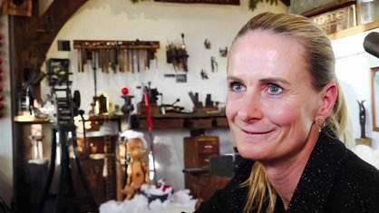Katrin Becker lächelt. Im Hintergrund eine Werkstatt.