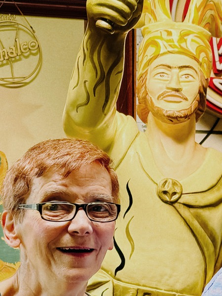 Ein Mann und eine Frau blicken in die Kamera, hinter ihnen eine Statue.