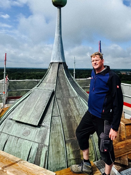 Gerald Plenter steht auf dem Gerüst der Baustelle um Schloss Raesfeld. Er steht ganz oben neben der Turmspitze. 
