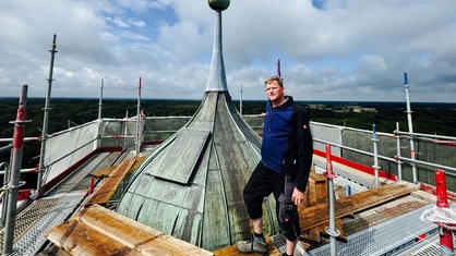 Gerald Plenter steht auf dem Gerüst der Baustelle um Schloss Raesfeld. Er steht ganz oben neben der Turmspitze. 
