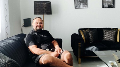 Ilia Vasilev sitzt auf einer Couch im Wohnzimmer.